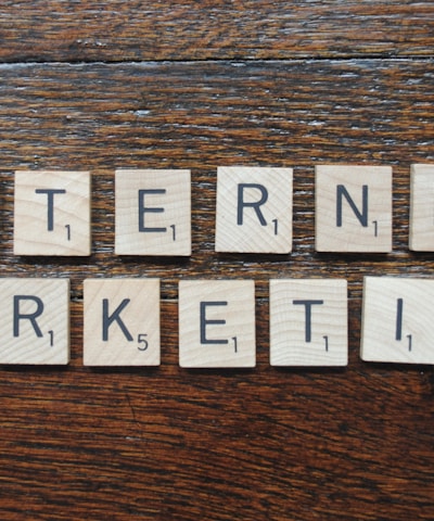 Wooden Scrabble tiles spell out the words 'INTERNET MARKETING' on a textured wooden surface.