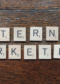 Wooden Scrabble tiles spell out the words 'INTERNET MARKETING' on a textured wooden surface.