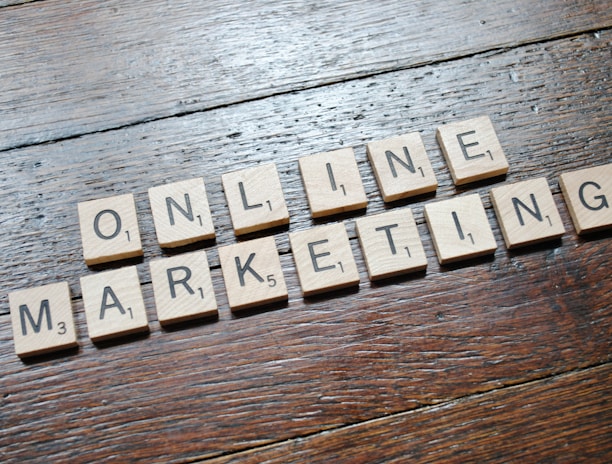 Scrabble tiles arranged to spell 'ONLINE MARKETING' on a wooden table with a textured surface.